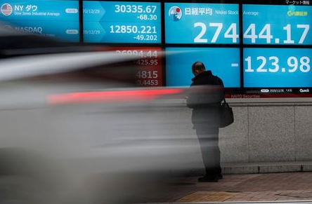 FILE PHOTO: A man stands in front of a screen displaying Nikkei share average and the world's stock indexes outside a brokerage, amid the coronavirus disease (COVID-19) outbreak, in Tokyo, Japan December 30, 2020. REUTERS/Issei Kato/File Photo