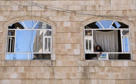 A girl looks from the window of her apartment in a building near a car workshop hit by a Saudi-led air strike, in Sanaa, Yemen December 7, 2021. REUTERS/Khaled Abdullah